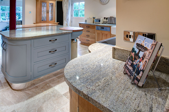 View across speckled granite worktops, Oak and painted kitchen.